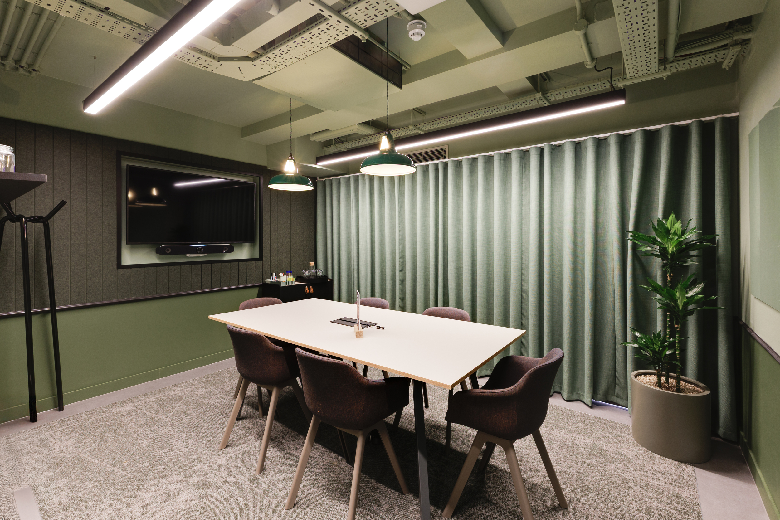 Meeting room at Work.Life Clerkenwell Green with green panelling, acoustic curtains and contemporary lighting, completed by Two.